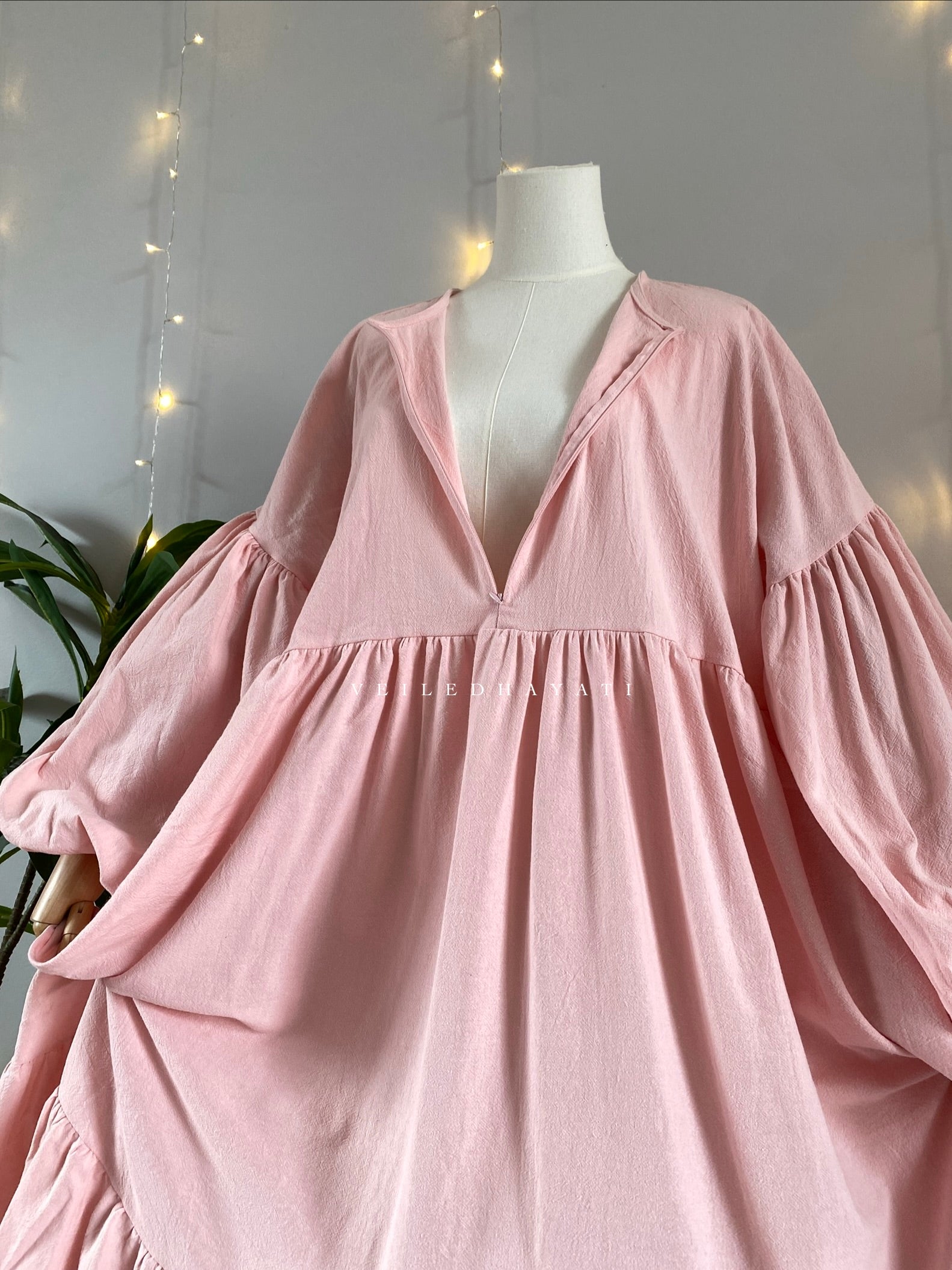 Mannequin wearing a pink organic 100% cotton abaya. Pastel light pink pure cotton abaya. Natural abaya with nursing friendly hidden zipper and deep pockets. Cute modest cotton abaya. All natural.