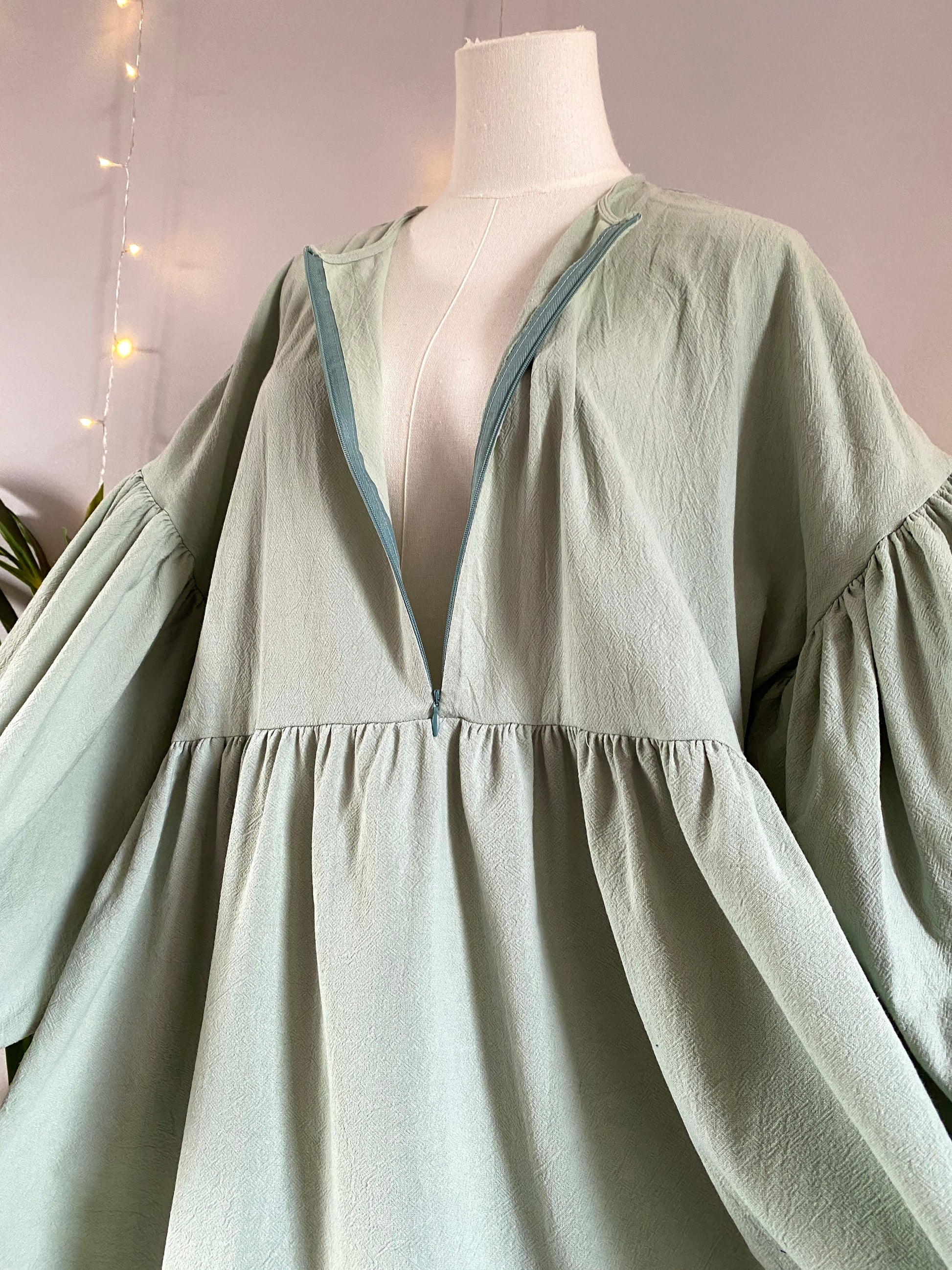 Mannequin wearing a pastel green organic 100% cotton abaya. Light green pure cotton abaya. Natural abaya with nursing friendly hidden zipper and deep pockets. Cute modest cotton abaya. All natural.