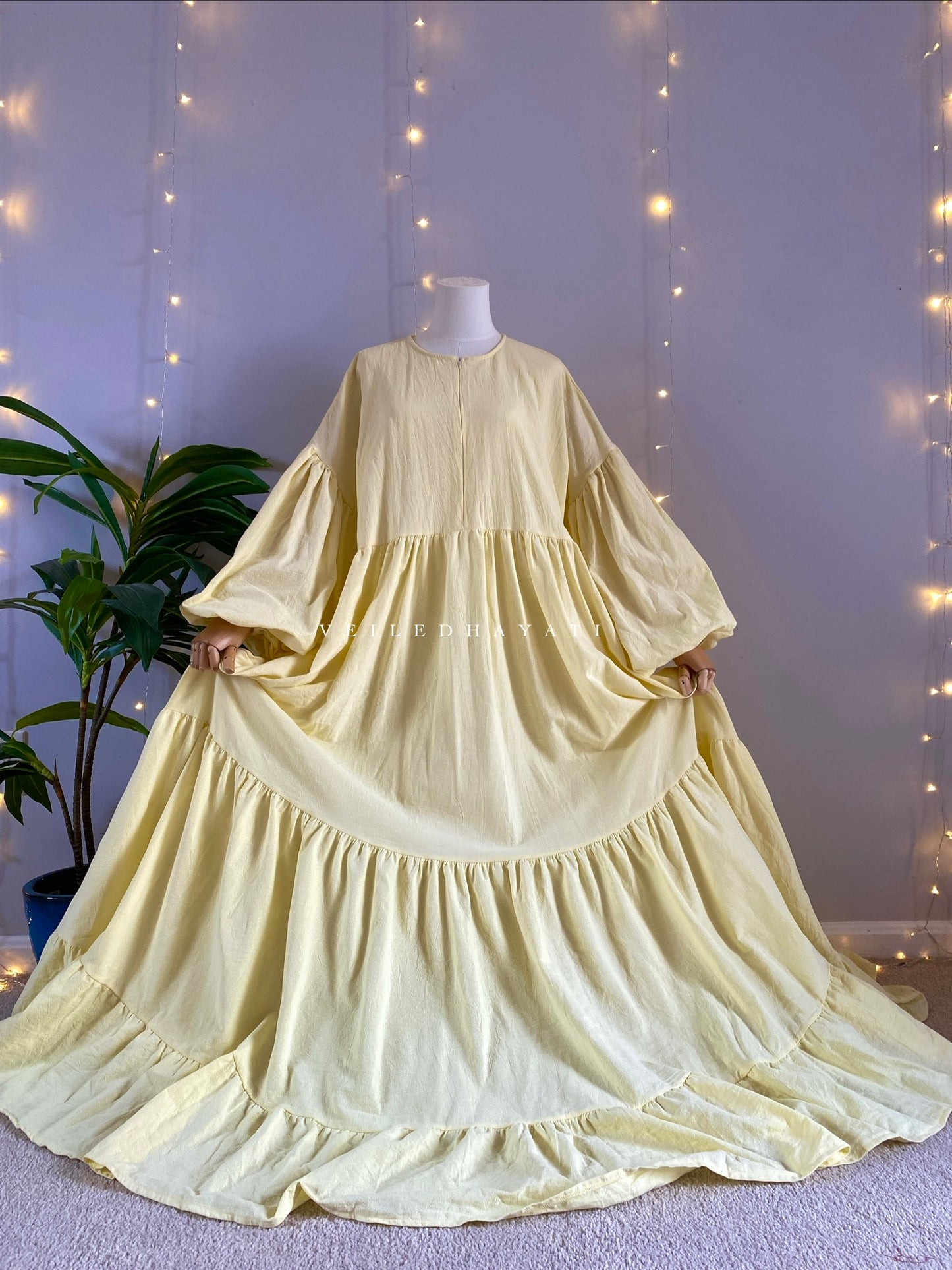 Mannequin wearing a butter yellow organic 100% cotton abaya. Pastel yellow pure cotton abaya. Natural abaya with nursing friendly hidden zipper and deep pockets. Cute modest cotton abaya. All natural.