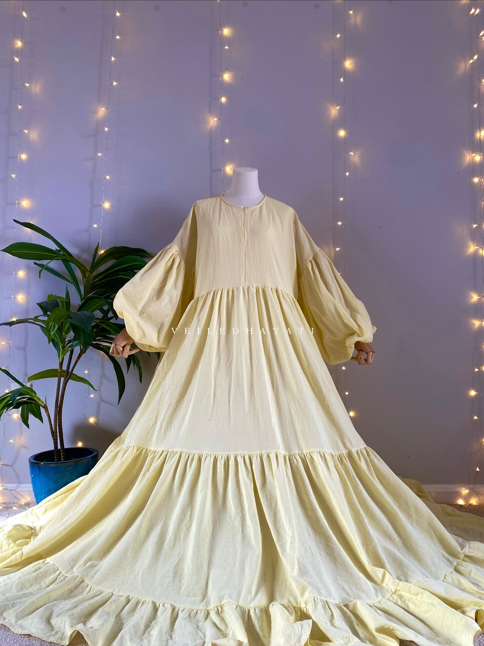 Mannequin wearing a butter yellow organic 100% cotton abaya. Pastel yellow pure cotton abaya. Natural abaya with nursing friendly hidden zipper and deep pockets. Cute modest cotton abaya. All natural.