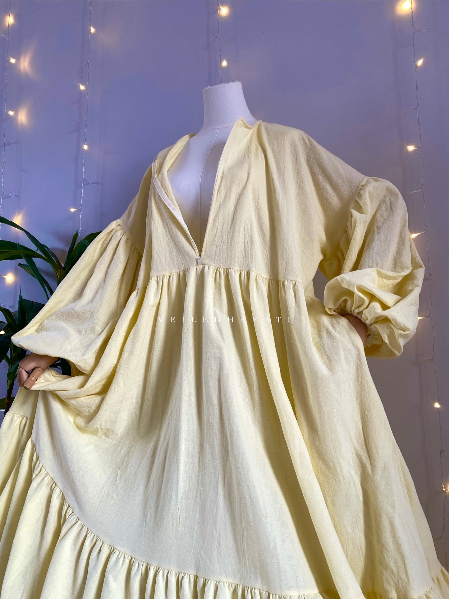 Mannequin wearing a butter yellow organic 100% cotton abaya. Pastel yellow pure cotton abaya. Natural abaya with nursing friendly hidden zipper and deep pockets. Cute modest cotton abaya. All natural.